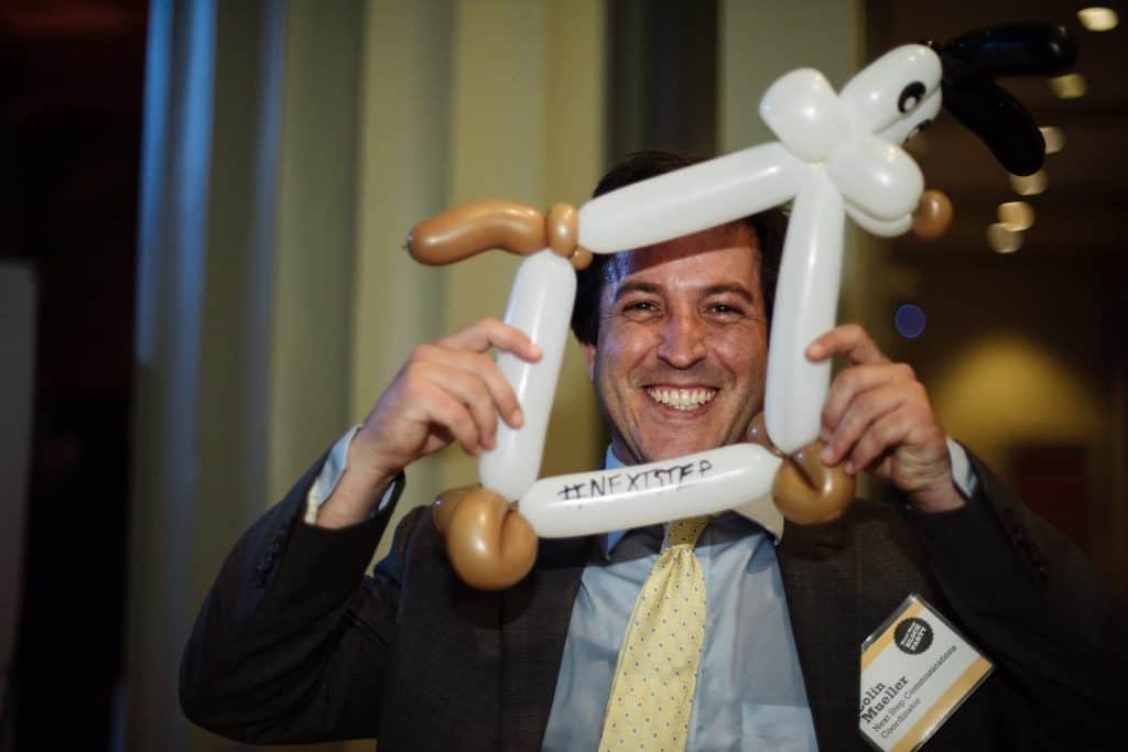 a man holding a balloon dog that is shapped as a photo frame